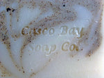 close up of a creamy white bar of soap with mossy green swirls and flecks