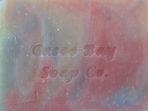 close up of creamy white bar of soap with red and blue swirls