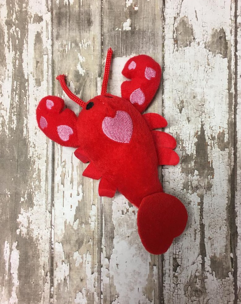 a red, soft, fuzzy and plush lobster with pink hearts