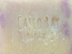 a close up of a creamy white bar of soap with light purple swirls