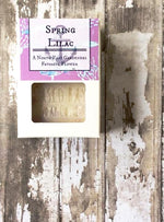 a white box with a cutout shows a creamy white bar of soap with light purple swirls