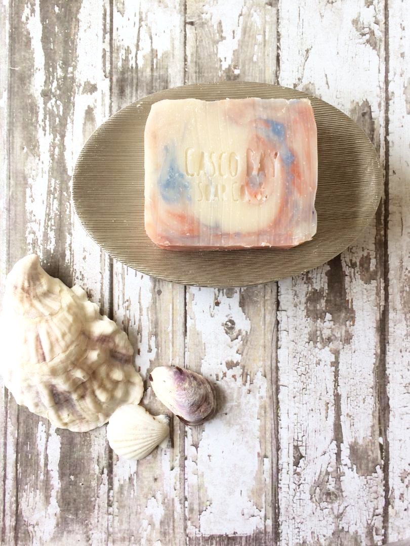 creamy white soap bar with blue and red swirls sits in a soap dish