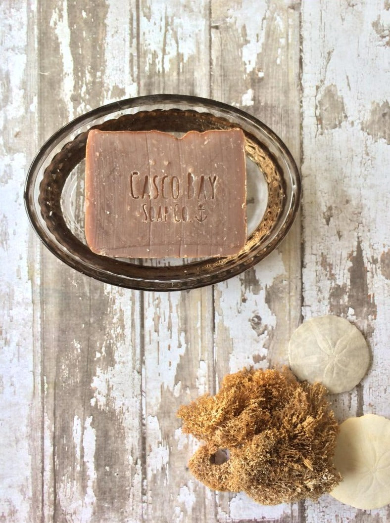 a light brown bar of soap sits in an oval soap dish