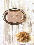 a light tan bar of soap sits in an oval soap dish