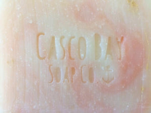 close up of creamy white bar of soap with pink swirls