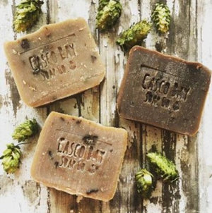 3 bars of soap in different shades of brown surronded by green hops