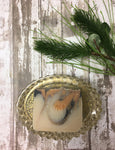 a creamy white bar of soap with black and orange swirls sits in a gold flecked soap dish