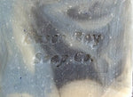 close up picture of a creamy white bar of soap with blue and black swirls