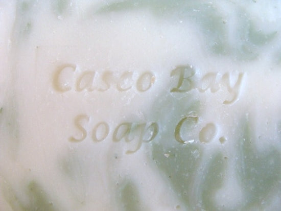 close up of off white bar of soap with green swirls