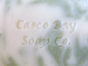 close up of off white bar of soap with green swirls